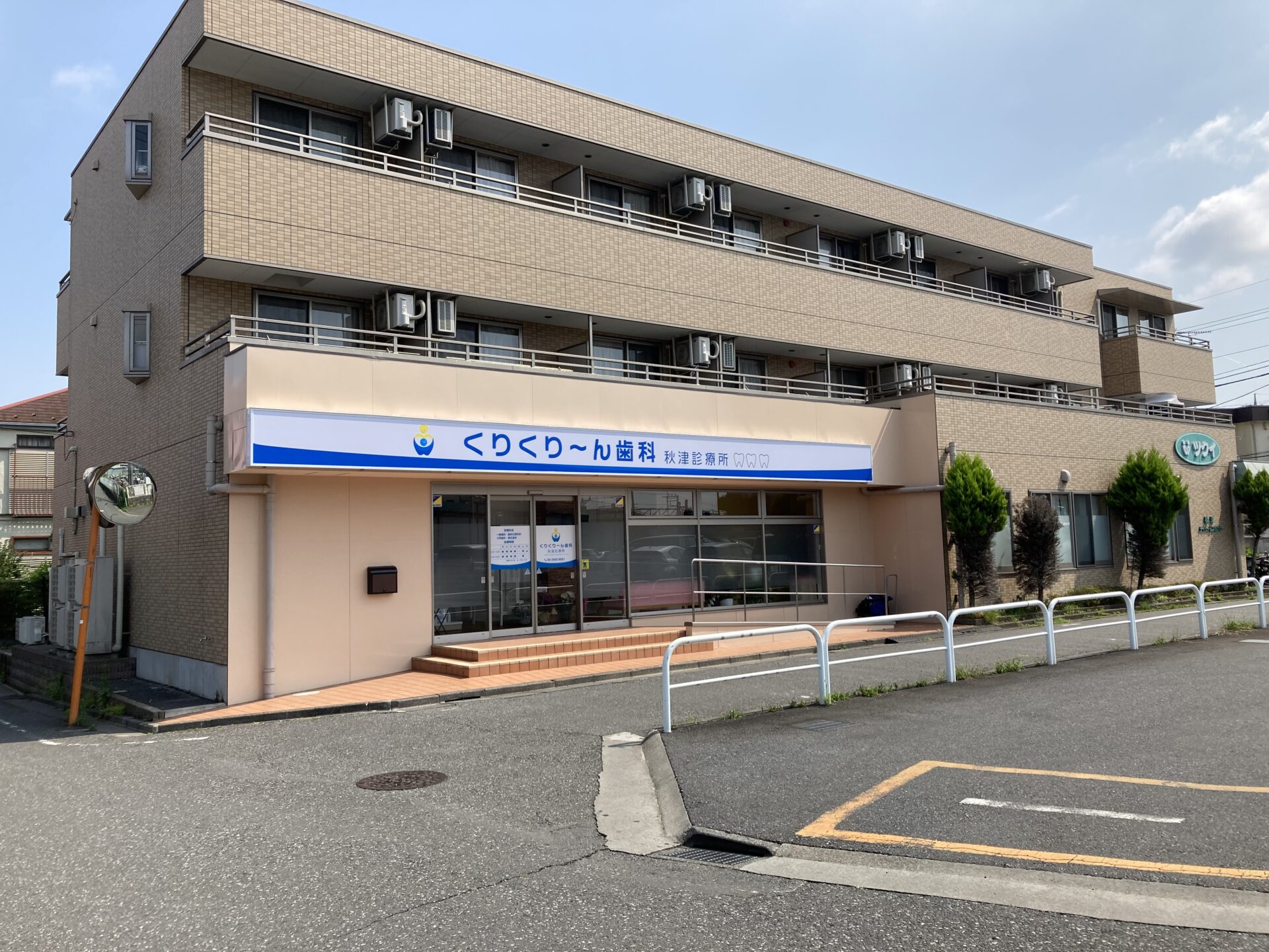 Beige brick building with a dentist office on the ground floor and a blue and white sign above the entrance.